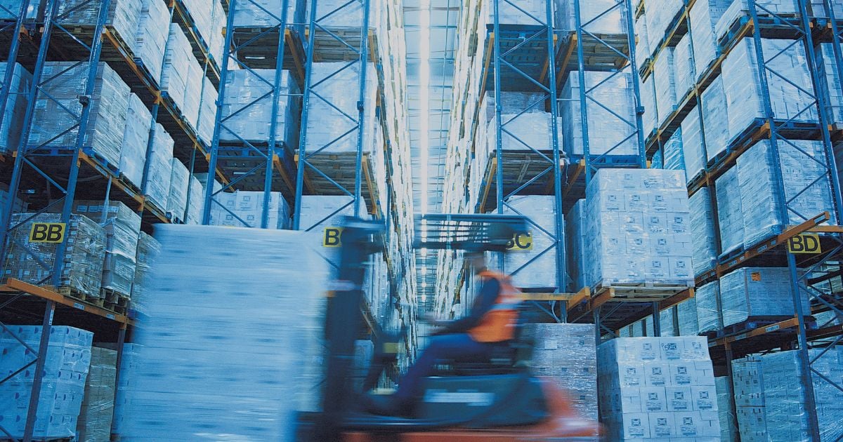 Worker driving a forklift in a full warehouse